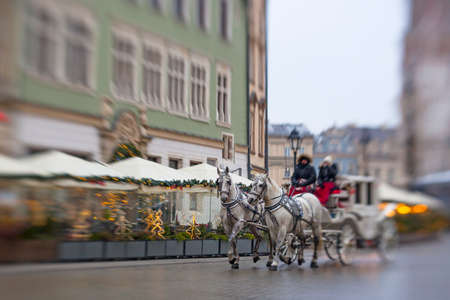 Krakow, Poland - December 9 2021: Horse carriages near St. Mary's Basilica and Christmas tree at Krakow market square, Poland.の写真素材