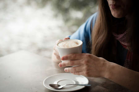 Beautiful young woman with a cup of tea at a cafeの写真素材