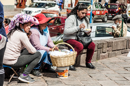 PERU - MAY 15, 2022: Peruvian people in traditional clothes  in Cuzco. Woman selling traditional food Tamalr in Cusco, Peru, May 15, 2022のeditorial素材
