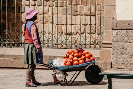 PERU - MAY 15, 2022: Peruvian people in traditional clothes in Cuzco. Girl sells pomegranates on the street. Cusco, Peru, May 15, 2022のeditorial素材