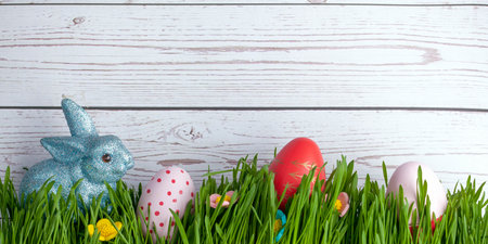 Easter composition with eggs, rabbit , sweet flowers  and grass, on the wooden background