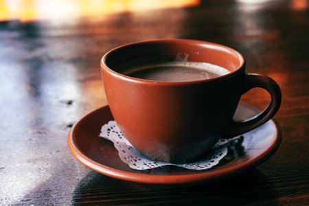 Fresh Americano coffee with milk in traditional  brown clay cup  on the wooden tableの写真素材