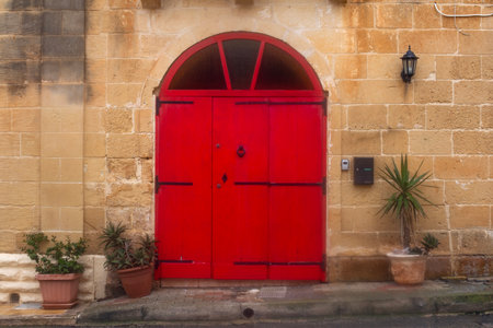 Red doors on the Narrow street of ancient city Rabat with traditional maltese houses built of limestone, Victoria, Maltaの写真素材