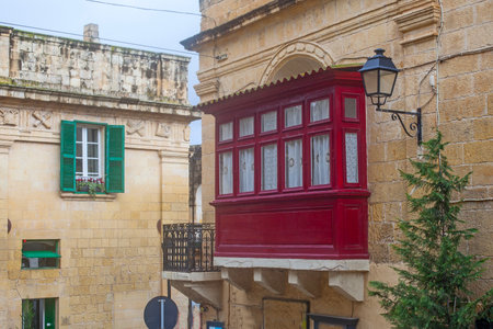 Red balcony on the narrow street of ancient city Rabat with traditional maltese houses built of limestone, Victoria, Maltaの写真素材
