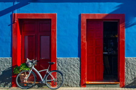 Buildings, street and parked bicycle on blue sky background. Colonial style of the city. Houses painted with various bright colors. Red barrelsの写真素材