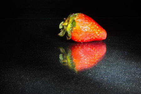 Garden strawberry on black background with reflectionの写真素材