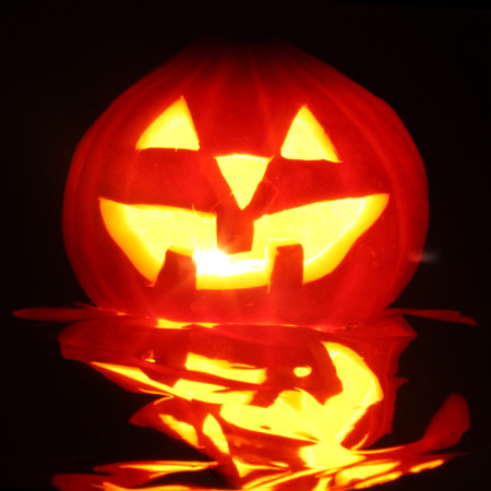 halloween pumpkin jack-o-lantern candle lit, isolated on black backgroundの写真素材