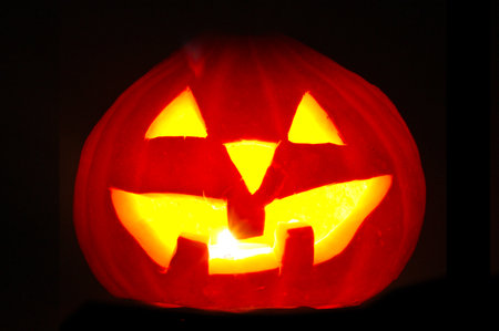 halloween pumpkin jack-o-lantern candle lit, isolated on black backgroundの写真素材