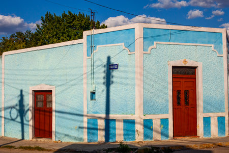 Merida, Yucatan, Mexico - 4 April, 2022: Street of Merida, Small bright light blue  colonial house with shadowsの写真素材