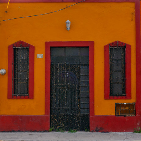 Small colonial style bright orange buildings at street of Merida city old town, Mexicoの写真素材