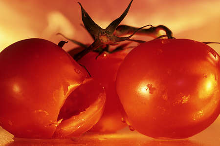 Close up of three red tomatoes with one cut.の写真素材