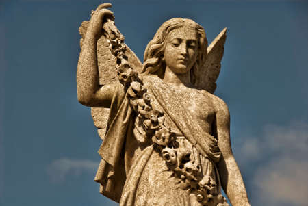 A stone angel holds a  garland of stone flowers.の写真素材