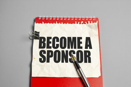 BECOME A SPONSOR, business concept text on a notepad page. on a red notebookの写真素材