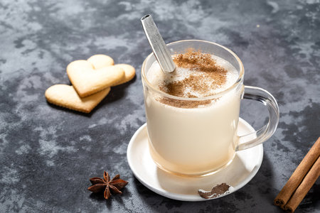 Glass mug with traditional Christmas drink homemade eggnog with cinnamon and heart shape cookiesの写真素材