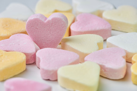 macro color photo of candy hearts lying on white background, one pink heart is standingの写真素材