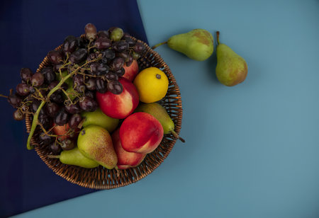 top view of fruits as basket of pear grape on blue background with copy spaceの写真素材