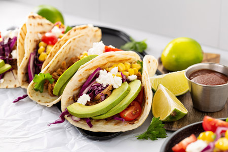 Pulled pork tacos with red cabbage, tomatoes, corn, feta and avocados overhead shot