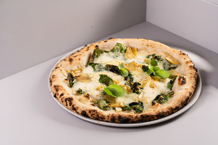 Pizza bianca or white pizza with cheese, artichokes and fresh basilの写真素材