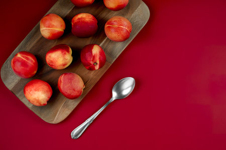 top view of juicy and delicious peaches on a wooden kitchen board on a red background with copy spaceの写真素材
