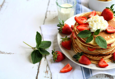 A stack of pancakes and strawberries on a wooden background