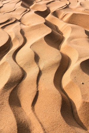 Close-up view of undulating sand dunes, showcasing the natural textures and patterns created by wind...
