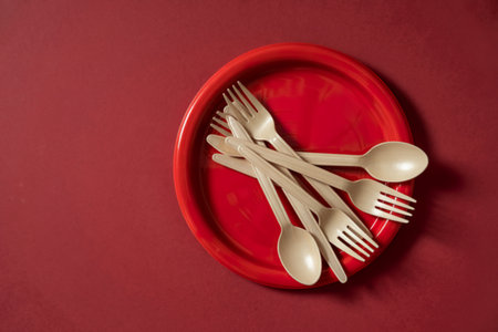 stack of plastic forks and spoons on red background, top view, copy spaceの写真素材