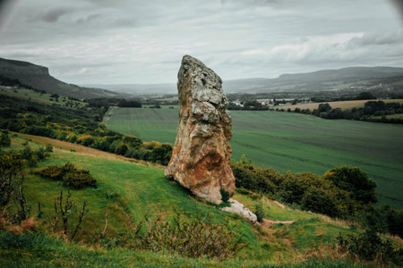 Old rock in green field landscape photo. Beautiful nature scenery photography with overcast sky on backgroundの写真素材