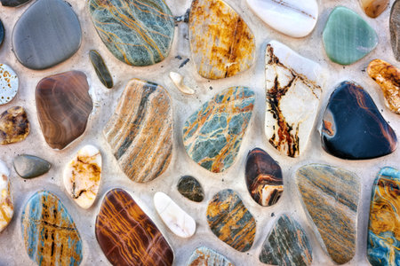 A close-up shot reveals a wall adorned with numerous polished stones of varying colors, shapes, and...