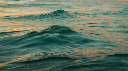 A captivating image of gentle ocean waves at sunset, showcasing a beautiful blend of teal and orange...