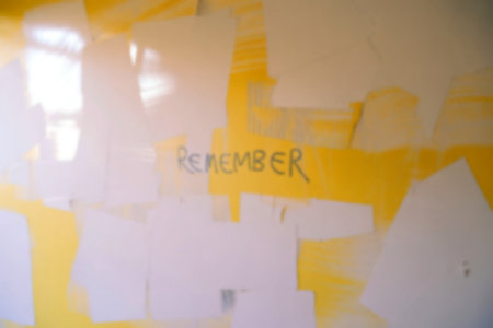 A yellow wall is being painted over with off-white paint, leaving patches of yellow visible. The word REMEMBER is written on the yellow section.の写真素材