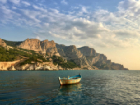 A weathered blue boat rests serenely in the calm waters, with dramatic coastal cliffs and a partly...