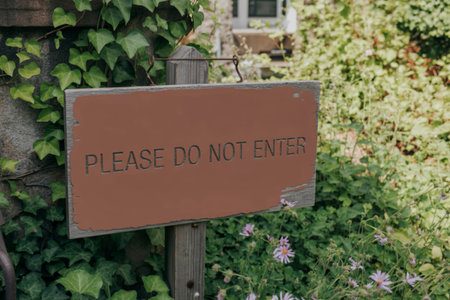 A weathered brown wooden sign with the words Please Do Not Enter, mounted on a post surrounded by...