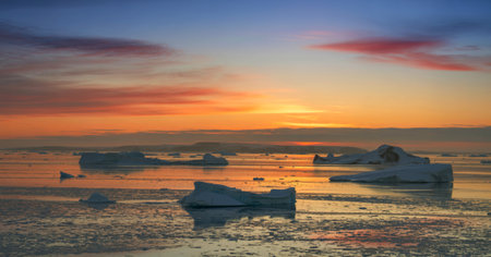 A breathtaking sunset paints the Arctic sky in vibrant pink and orange hues, casting a warm glow on...