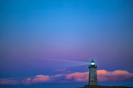 A solitary lighthouse stands tall, its beam cutting through the twilight sky above a layer of soft pink clouds. The scene evokes a sense of hope and guidance.の素材