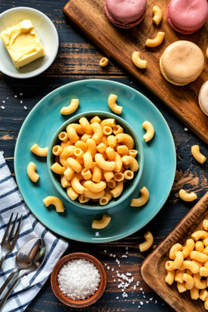 top view of different macaronis in bowl salt butter around plate on wooden background