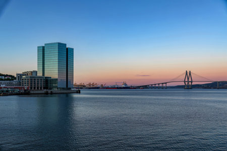Modern cityscape with harbor and cable stayed bridge at sunset