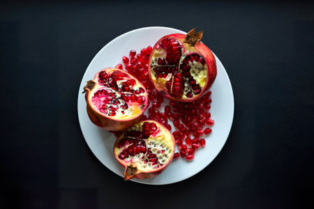 top view cut pomegranate on a white plate on a black background