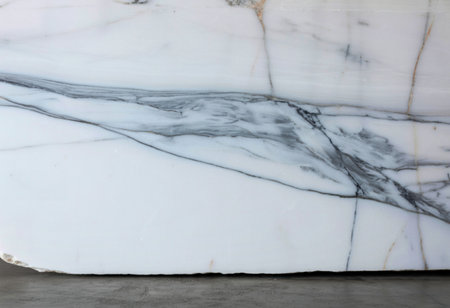 A close-up view of a polished white marble slab showcasing striking gray veining and delicate golden streaks, highlighting its natural beauty and texture.の写真素材