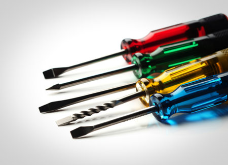 A collection of screwdrivers with translucent, brightly colored handles in red, green, yellow, and blue, laid out on a clean white surface.の写真素材