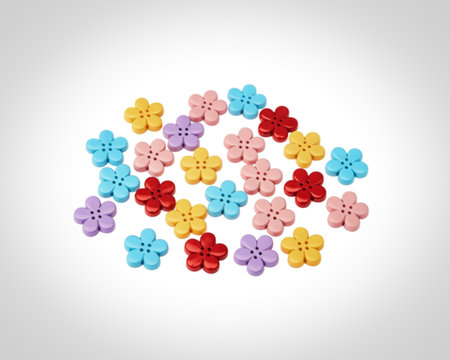 A collection of small, plastic, flower-shaped buttons in various bright colors including pink, yellow, blue, purple, and red, arranged randomly on a clean white surface.の写真素材