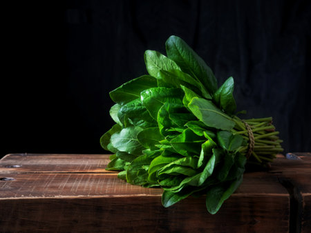 fresh green leaves of sorrel are bound in a bunch on a wooden table, black backgroundの写真素材