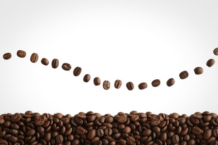 A collection of roasted coffee beans is arranged in a curved line against a white background, with a dense pile of beans filling the bottom of the frame.の写真素材