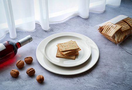A bottle of rose wine, stacked crackers, and scattered nuts are artfully arranged on a textured...