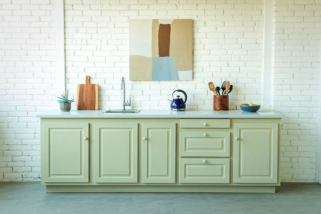 A stylish kitchen vanity with light green cabinets, a marble countertop, and a contemporary abstract...