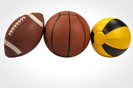 A brown American football, a brown basketball, and a yellow and black volleyball are displayed side by side on a white background.の写真素材