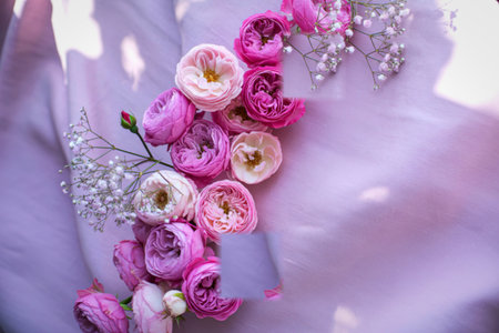 A close-up view of a floral arrangement featuring soft pink and white roses with intricate silver accents on a light, flowing fabric.の写真素材