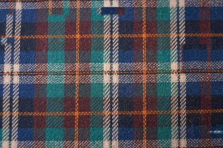 A close-up view of a woven fabric featuring a traditional plaid pattern with intersecting lines of blue, green, red, and white.の写真素材
