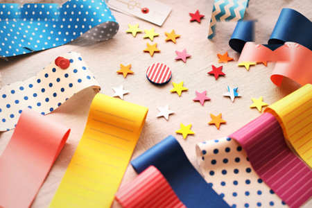 A vibrant collection of patterned and solid ribbons, along with small star-shaped embellishments, laid out for crafting and decorating.の写真素材