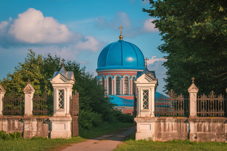 An old stone gate with decorative pillars stands before a striking blue-domed church, surrounded by...