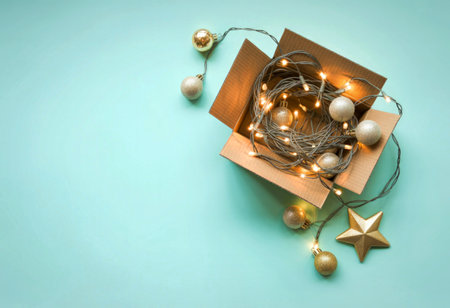 A cardboard box filled with string lights and various Christmas ornaments, including a star and...